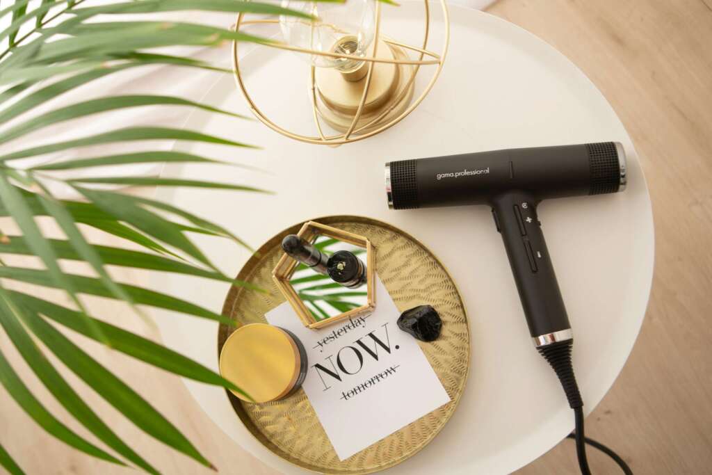 Collection of hair styling tools including a dryer, straightener, and scissors with a plant