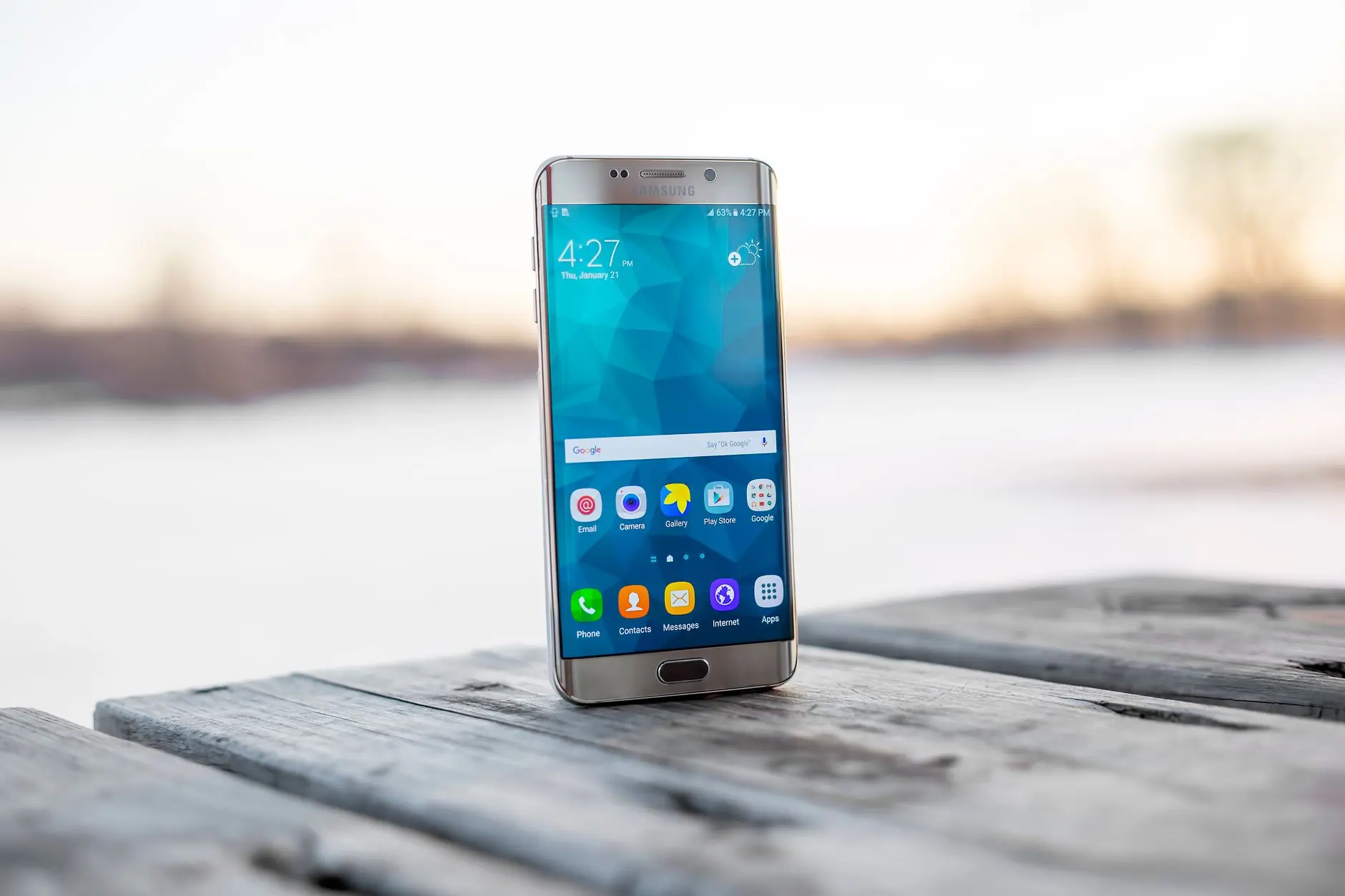 Samsung Galaxy smartphone with a colorful screen on a wooden table.