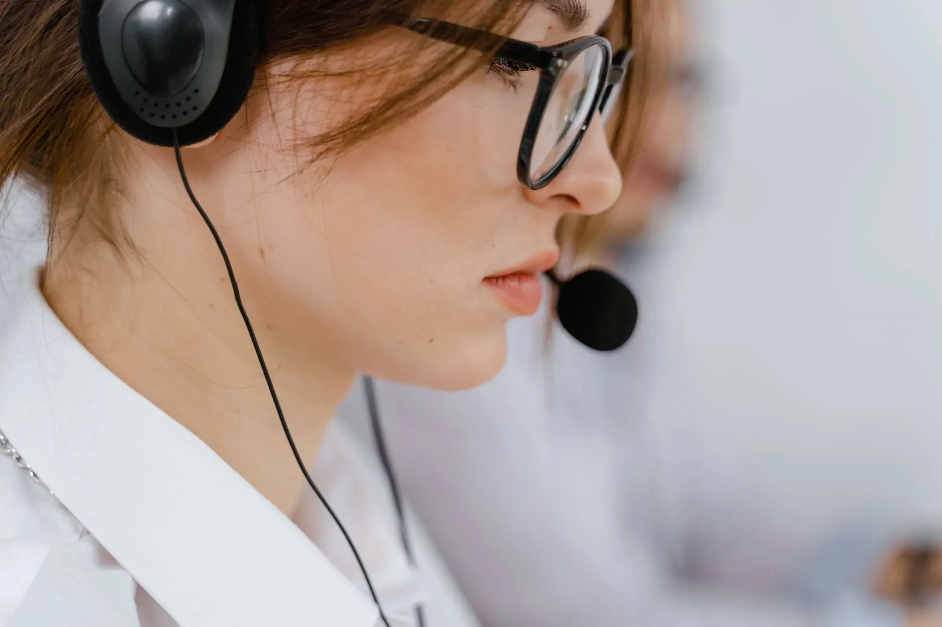 Two-panel image of a woman with headphones at a desk in an office, shown from close-up left and distant right.
