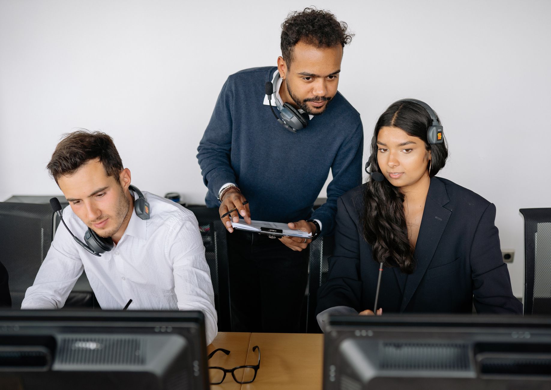 Three coworkers in a modern office discuss a tablet showing a diagram